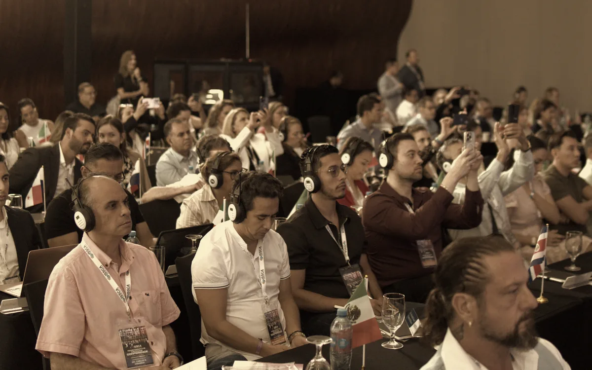 Médicos en una conferencia ISSCA siguiendo una sesión con auriculares de traducción